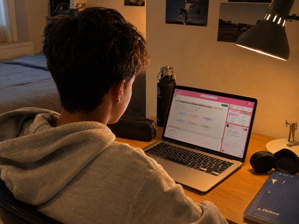 Un adolescent en sweat révise sur DYS-Cours sur son ordinateur portable dans sa chambre
